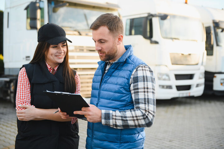 Two people looking at a tablet with buses in the backdrop.